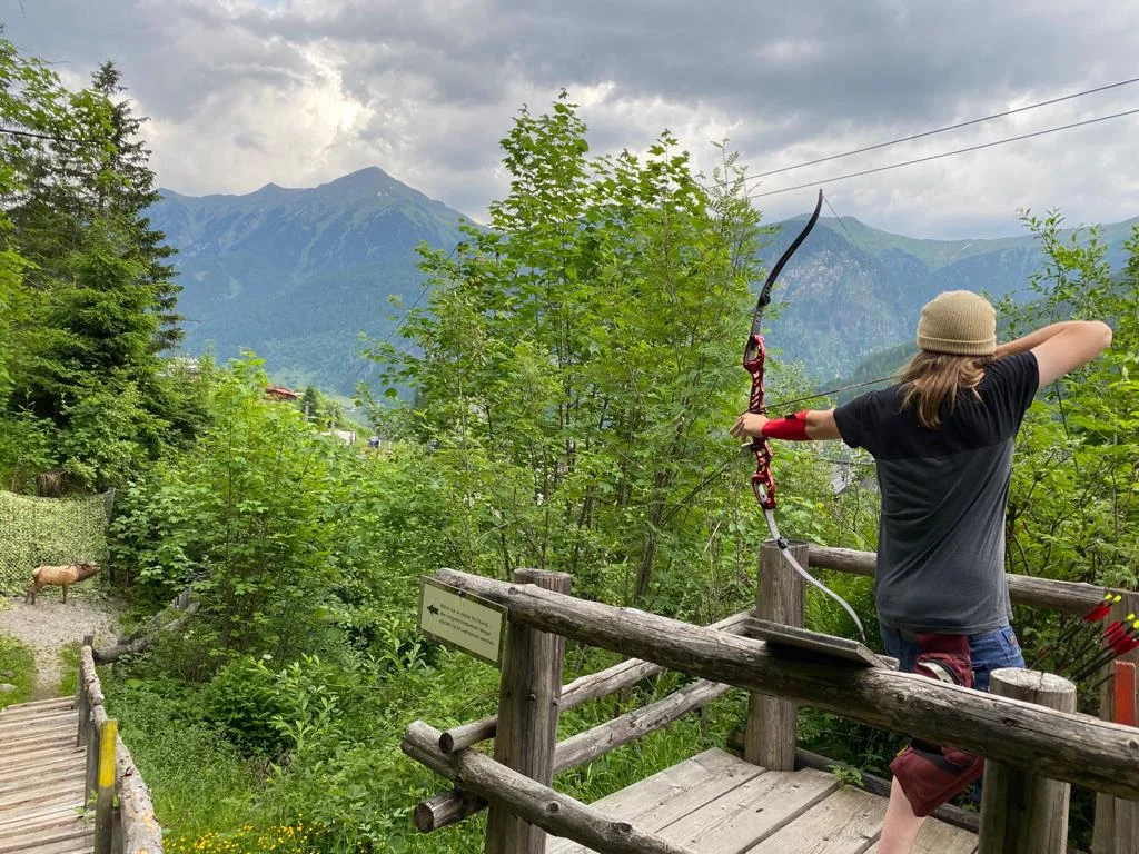 Bogenschütze beim Anvisieren eines 3D-Ziels im Wald